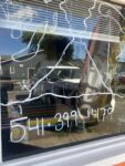 Hand-painted white volcano labeled Volcan de Colima and a phone number on the front window of Mi Lindo Colima Mexican restaurant in Odell, Oregon